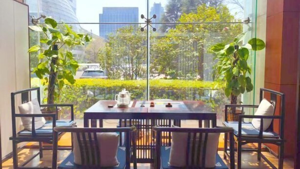 A dining area with a table and chairs, a view of greenery and buildings through large windows. - Jinyang Hotel (Exhibition Center Store)） (Guiyang)