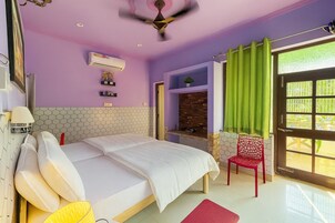 A bedroom with a bed, a red chair, a green curtain, and a ceiling fan.