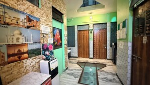 A hallway with a marble floor, a water dispenser, and a wall with posters of landmarks. - Anukampa Guest House (Agra)