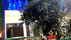 A building with blue lighting and a tree in the foreground. - Anukampa Guest House (Agra)