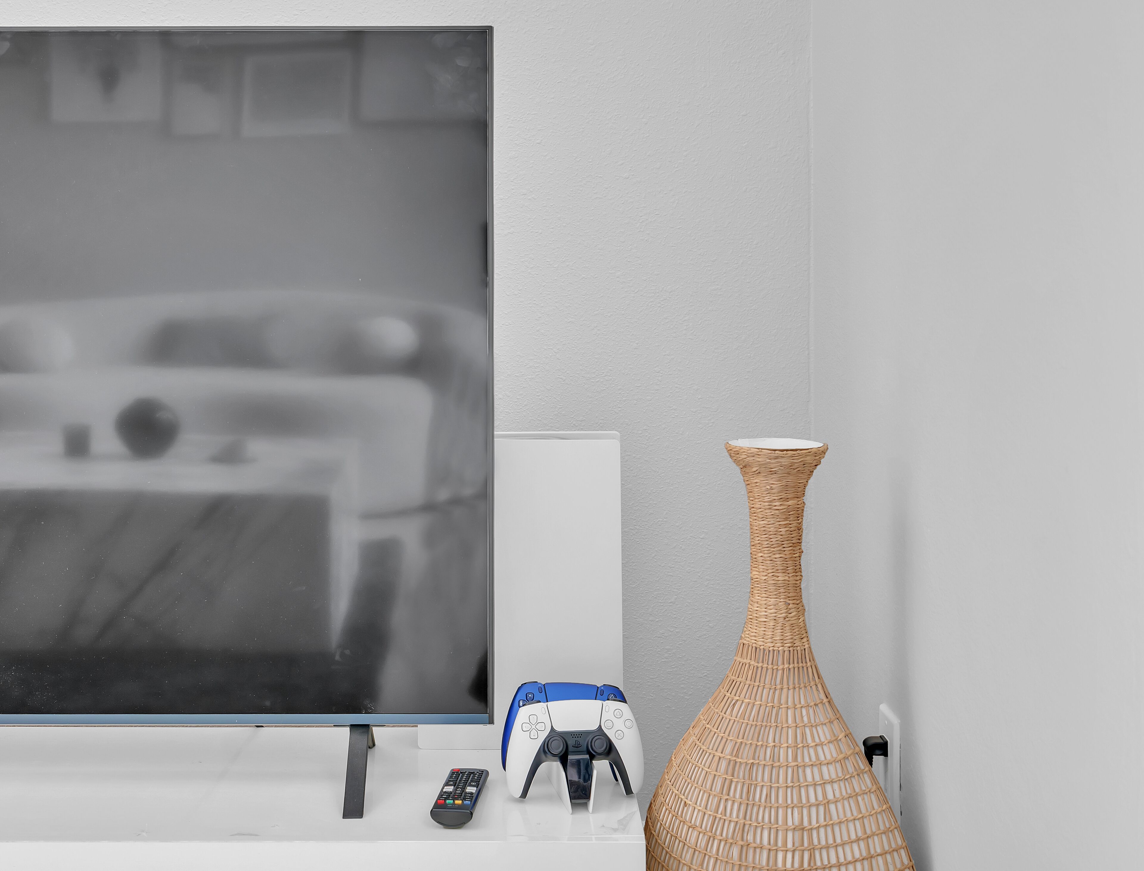 Ein Fernseher, eine Fernbedienung und ein Spielcontroller auf einer weißen Oberfläche.