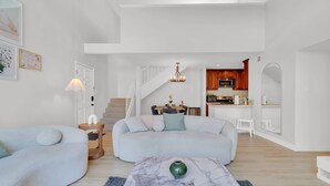 Ein modernes Wohnzimmer mit einem Marmortisch, einem hellblauen Sofa und einem Essbereich mit einer Treppe.