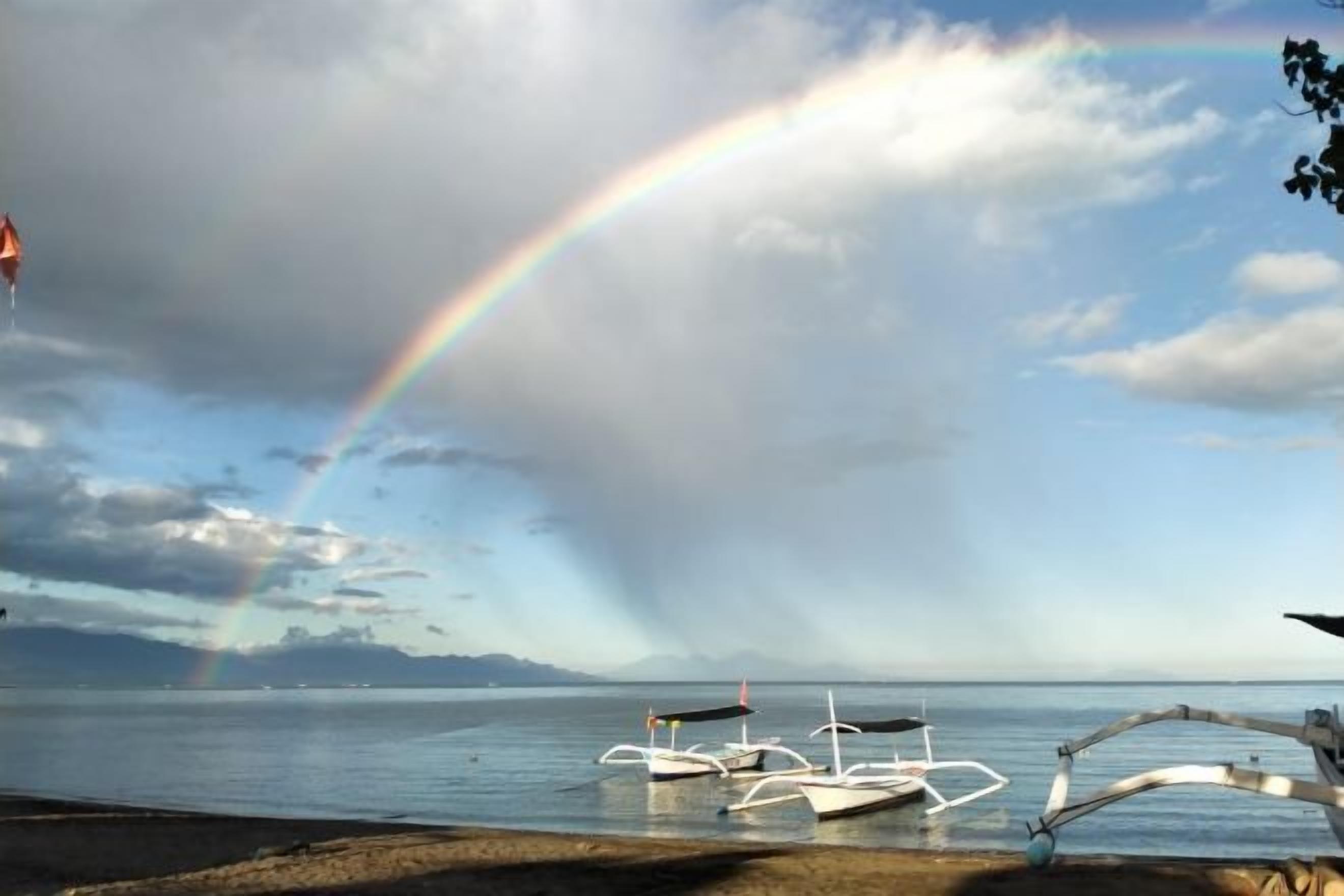 A beach with boats and a rainbow.