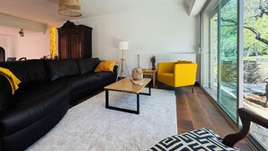 A modern living room with a black sofa, a yellow armchair, and a wooden coffee table.