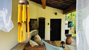 A cozy outdoor seating area with a wooden bench, a woven sofa, and a hanging chair.