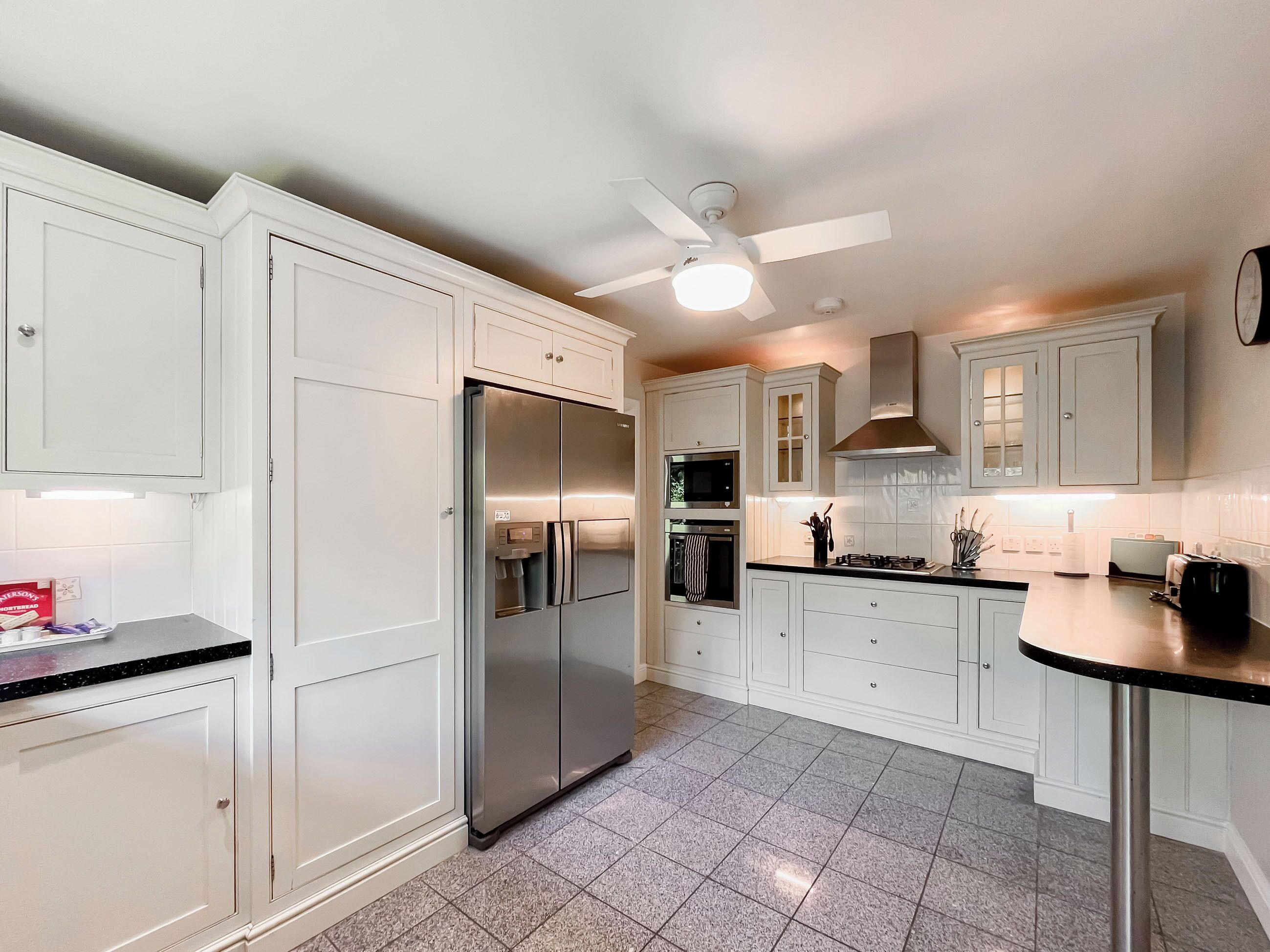 A modern kitchen with white cabinetry, a stainless steel refrigerator, a microwave, an oven, and a gas stove.