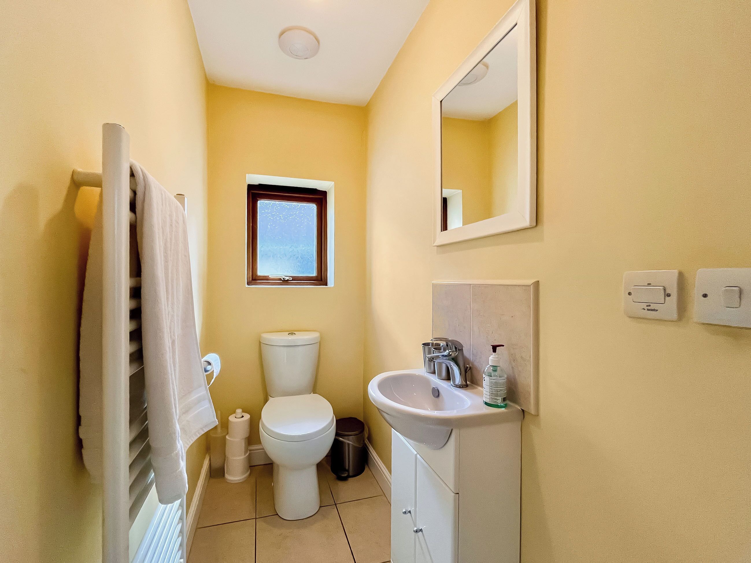 Een kleine badkamer met toilet, wastafel en een klein raam.
