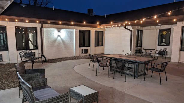 Eine Außenpatio-Terrasse mit Esstisch, Stühlen und einer Sitzgruppe.