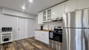 Eine moderne Küche mit weißen Schränken, einem Edelstahl-Kühlschrank, einer Mikrowelle und einer Holz Arbeitsplatte.