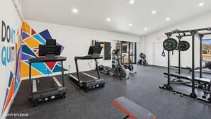 Ein Fitnessraum mit Laufbändern, einer Bank und Gewichten.