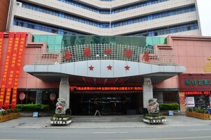 Un edificio con una entrada amplia, pancartas rojas y dos estatuas.