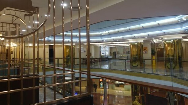 A modern interior with a glass railing, a central decorative element resembling a deer, and a spacious, multi-level layout. - Gold Deer Hotel (Nan'an)