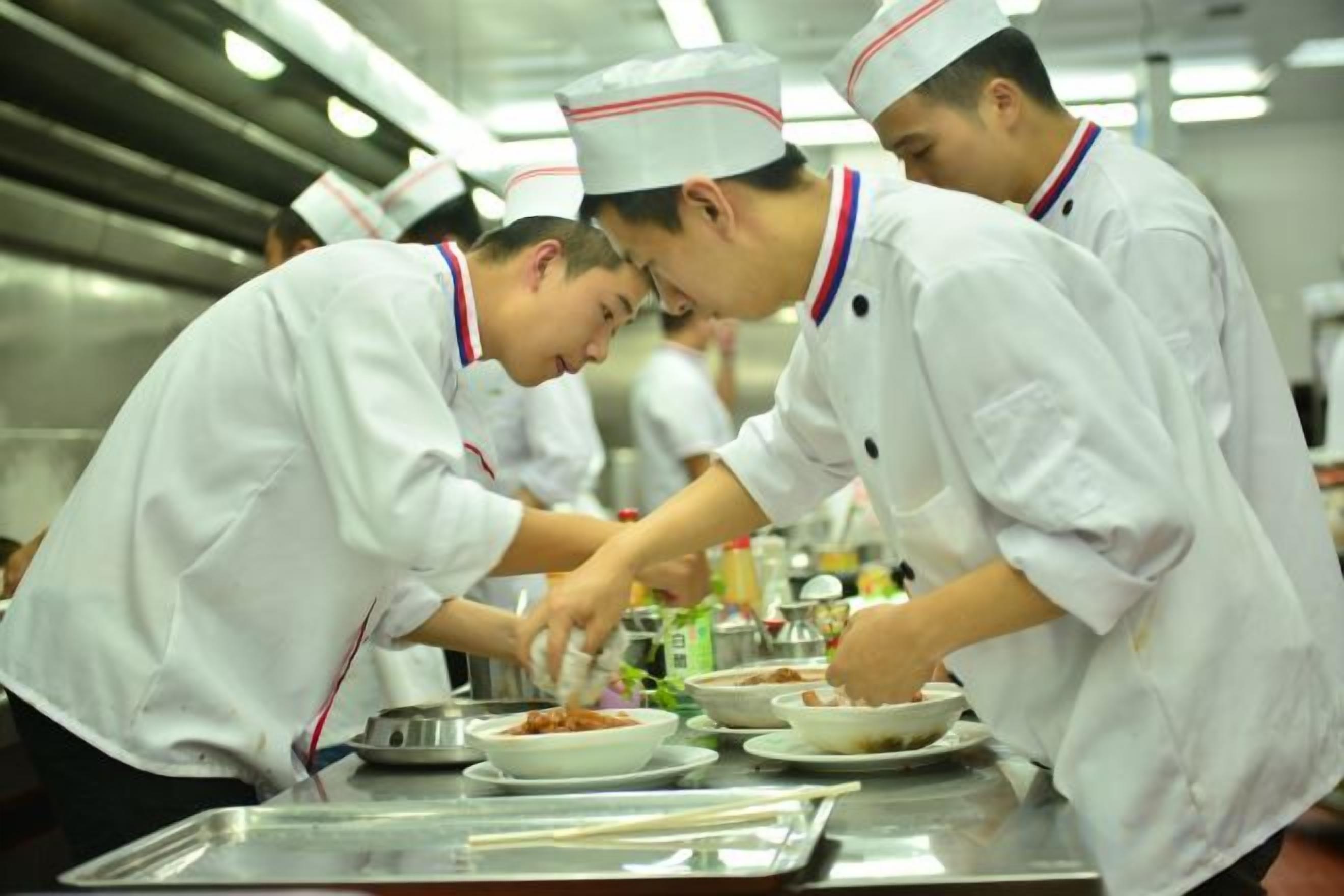 Chefs in white uniforms preparing food in a kitchen.