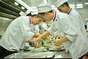 Chefs in white uniforms preparing food in a kitchen. - Gold Deer Hotel (Nan'an)