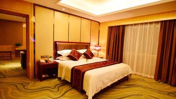 A hotel room with a large bed, a bedside table with a lamp, a mirror, and a view of a window with curtains.
