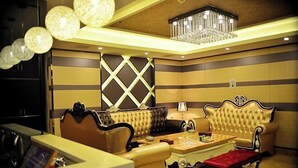 A luxurious living room with a chandelier, leather sofas, a coffee table, and a patterned wall. - Gold Deer Hotel (Nan'an)