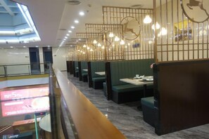 A restaurant with booths and a long counter, modern lighting fixtures, and a visible menu screen. - Gold Deer Hotel (Nan'an)