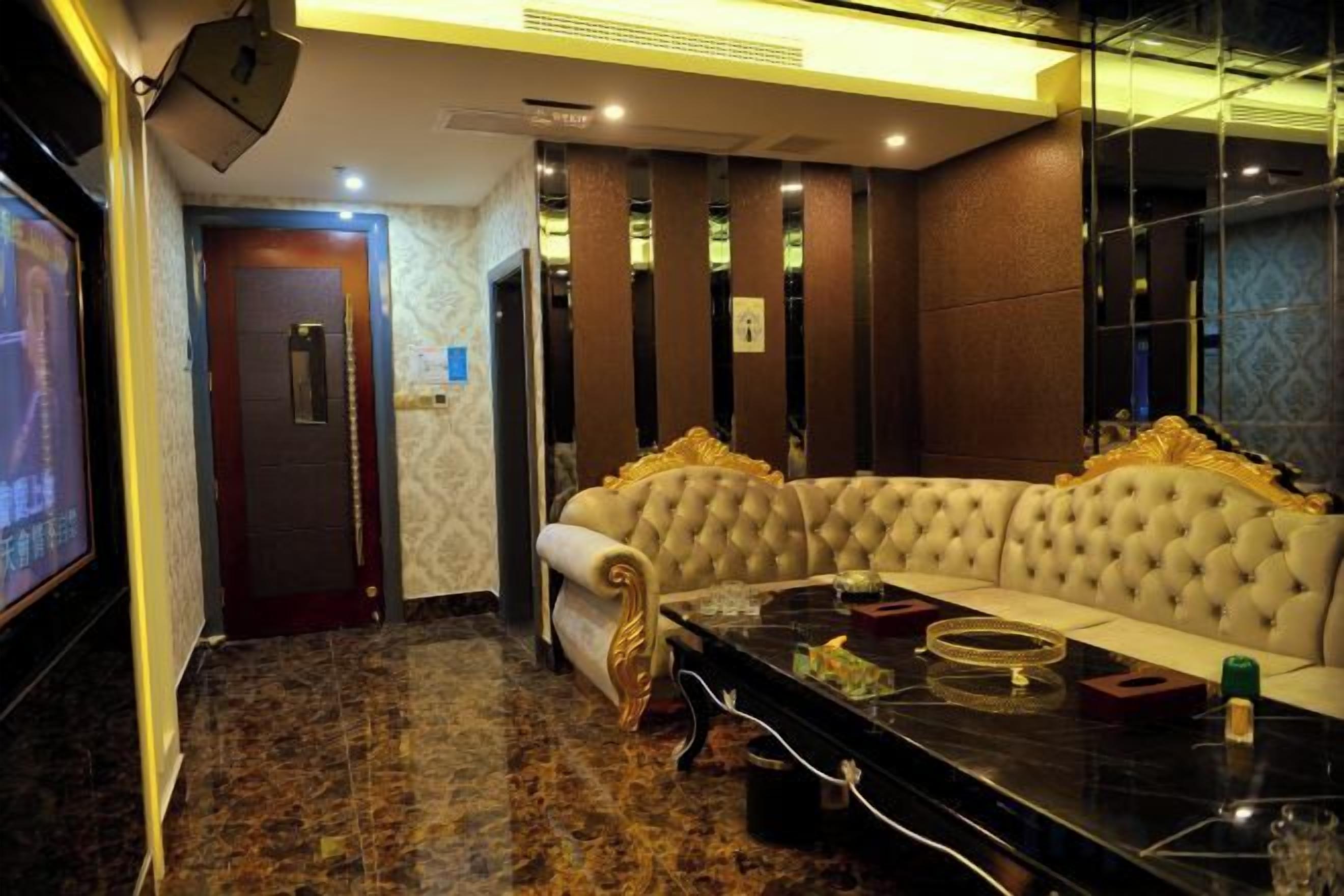 A room with a large, tufted sofa, a flat-screen TV, and a marble coffee table.
