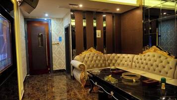 A room with a large, tufted sofa, a flat-screen TV, and a marble coffee table.