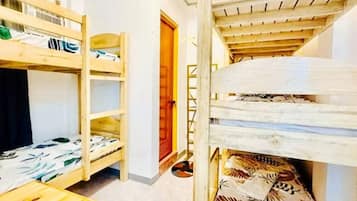 A room with bunk beds, a wooden staircase, and a door leading to another area.