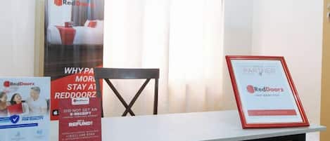 A table with promotional materials for RedDoorz, including a framed certificate, a poster, and a brochure.