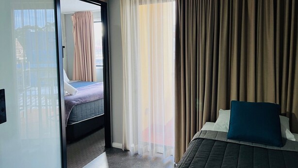 Habitación de hotel con cama, ventana con cortinas y vistas al exterior.