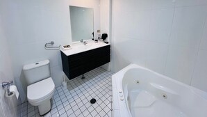 Un baño moderno con inodoro, lavabo, espejo y bañera.