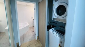 Une petite buanderie comprenant un lave-linge, un sèche-linge et un petit évier.