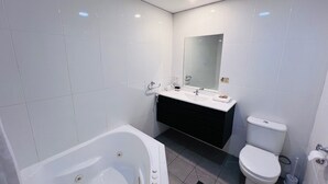 Une salle de bain moderne avec une baignoire, un lavabo avec un miroir et des toilettes.