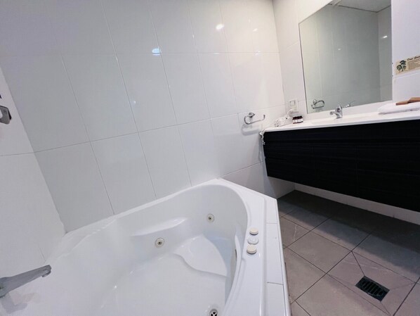 Un baño moderno con una bañera blanca, un tocador negro y un espejo grande.