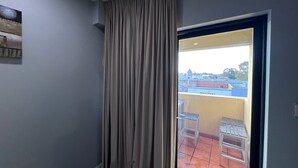 Une pièce dotée d’une porte-fenêtre coulissante donnant sur un espace extérieur avec un sol carrelé et une table.
