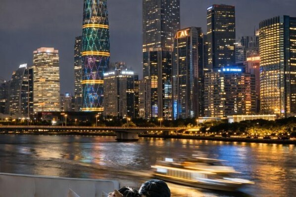 A nighttime cityscape with illuminated skyscrapers along a river.