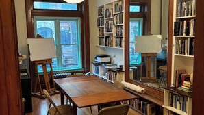 Una habitación con una mesa de madera, dos sillas, un espejo grande y estanterías llenas de libros.