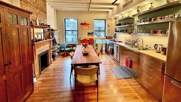 Una cocina amplia con suelos de madera, una mesa de comedor y una pared de ladrillo.