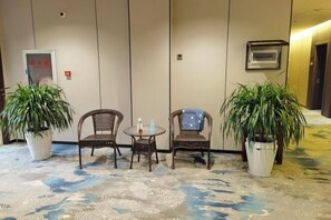 Una habitación con dos sillones de mimbre, una mesita pequeña y dos plantas en macetas.