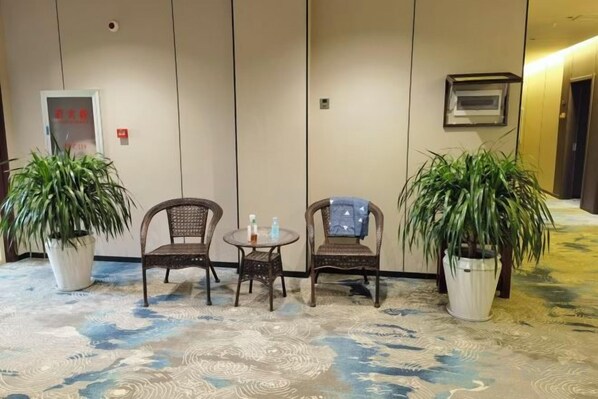 A room with two wicker chairs, a small table, and two potted plants. - Qingxu Haitianyu Hotel (Qingxu)