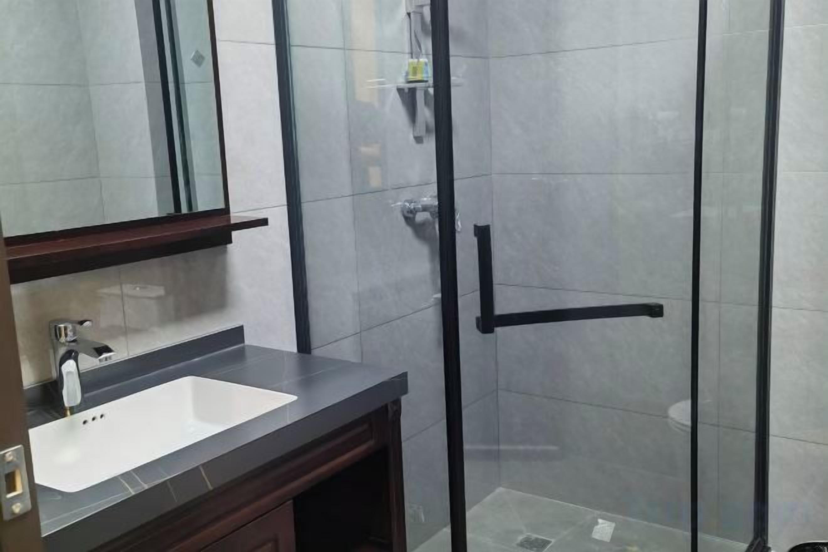 Un baño con cabina de ducha de vidrio, un lavabo y un espejo.