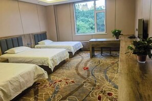 Camera d'albergo con due letti, una scrivania in legno, una TV e una finestra con vista sul verde.