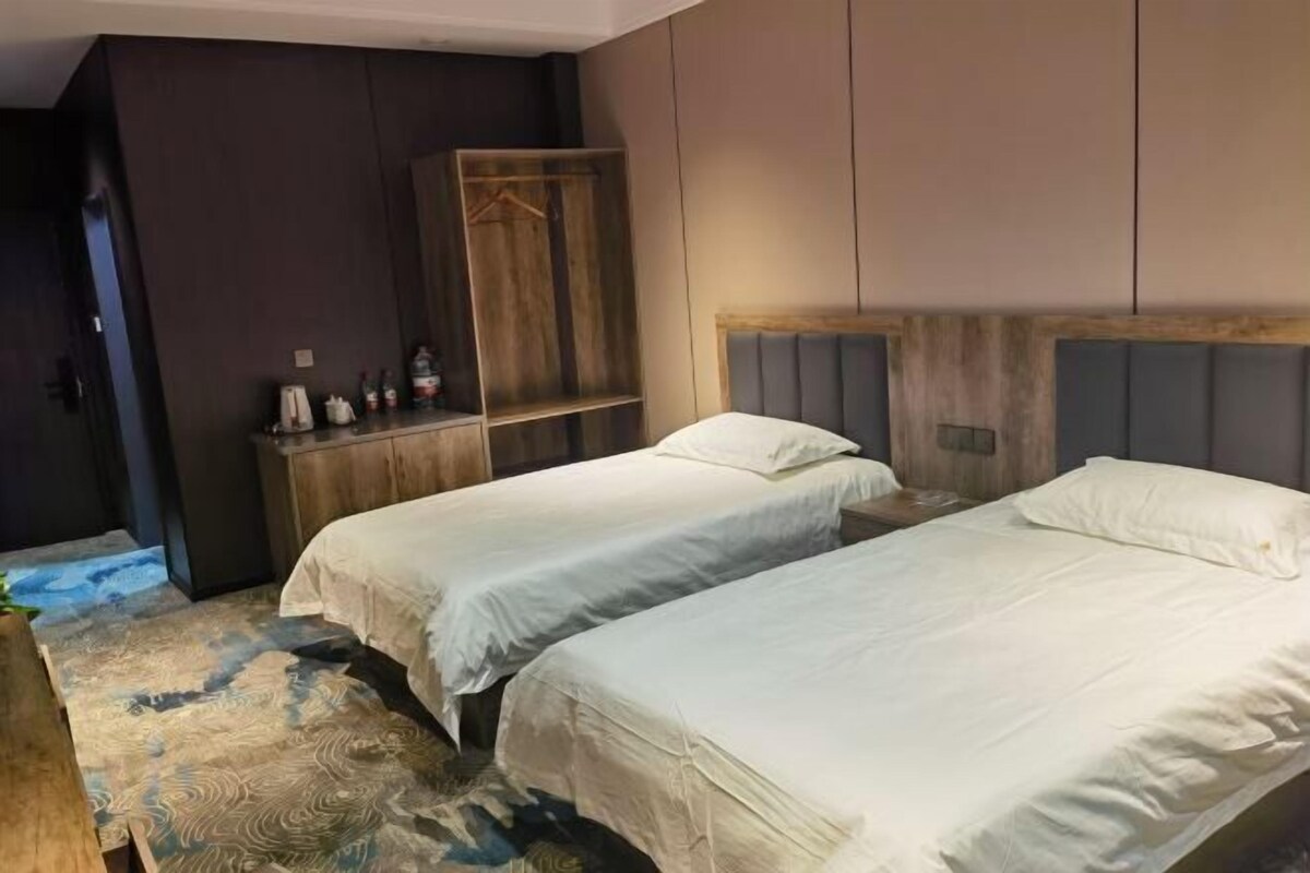 Una camera d'albergo con due letti, un armadio in legno e un tappeto decorato.