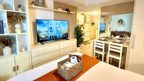 A hotel room with a television, a bed, a dining area, and a bathroom. - Solei Oak: Pet Friendly Studio with Netflix, Boardgames, Beach & Mt. Arayat View (San Fernando)