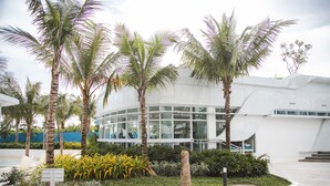 A modern building with a glass facade, surrounded by palm trees and tropical plants. - Solei Oak: Pet Friendly Studio with Netflix, Boardgames, Beach & Mt. Arayat View (San Fernando)