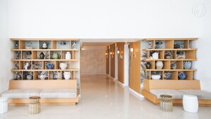 A modern hotel lobby with two wooden shelving units filled with decorative items, a central seating area, and a clean, tiled floor. - Solei Oak: Pet Friendly Studio with Netflix, Boardgames, Beach & Mt. Arayat View (San Fernando)