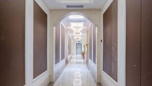 A long, narrow hallway with a polished floor, white walls, and a central archway. - Shishi Laiya Fortune Hotel (Quanzhou South Railway Station) (Shishi)