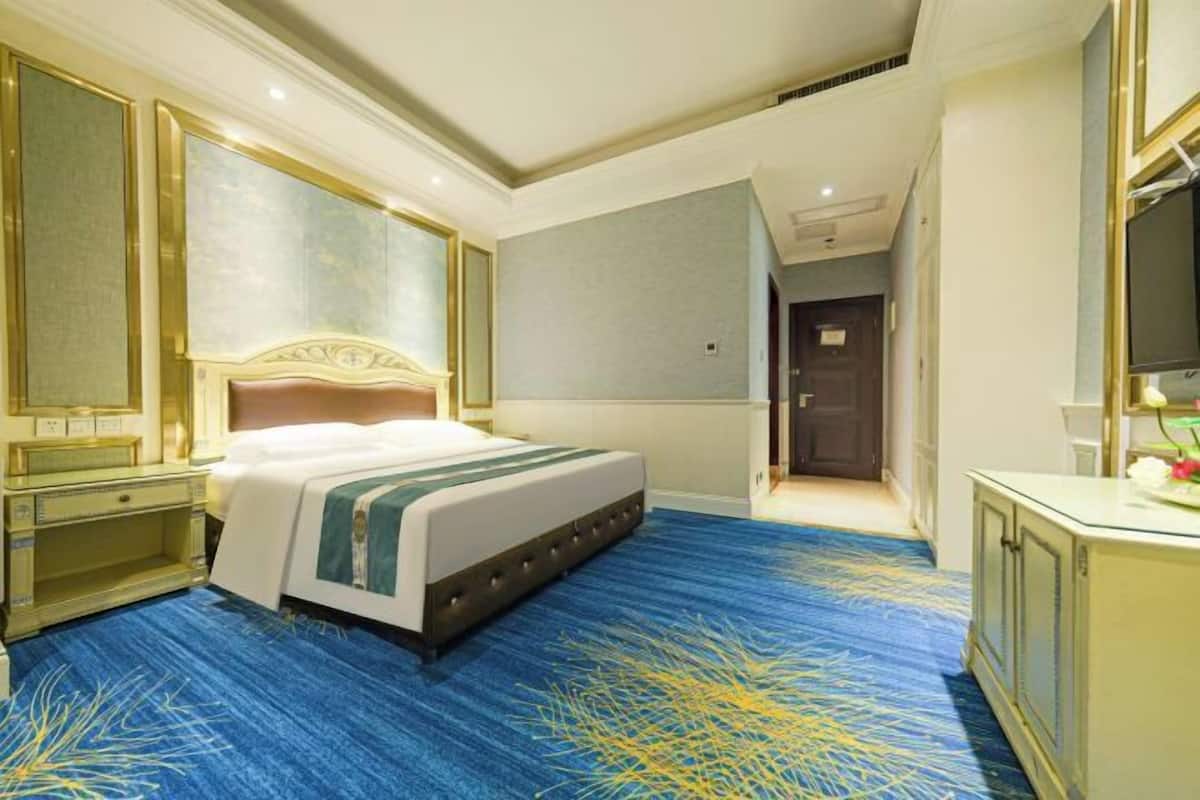 Une chambre d’hôtel avec un grand lit, un bureau, une commode et un miroir.