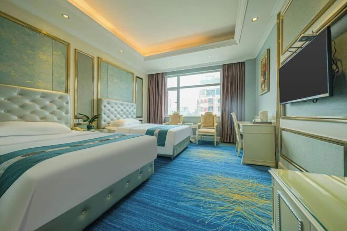 Une chambre d’hôtel avec deux lits, un téléviseur à écran plat, un bureau et une grande fenêtre.