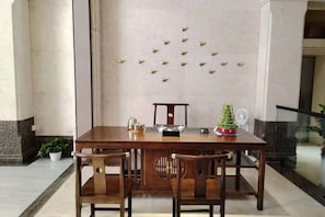 Una mesa de comedor de madera con sillas, un pequeño árbol de Navidad y una pared decorativa con detalles dorados.