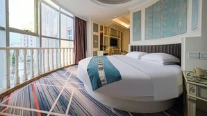 A hotel room with a large bed, a desk, a phone, and a view of the city through large windows. - Shishi Laiya Fortune Hotel (Quanzhou South Railway Station) (Shishi)