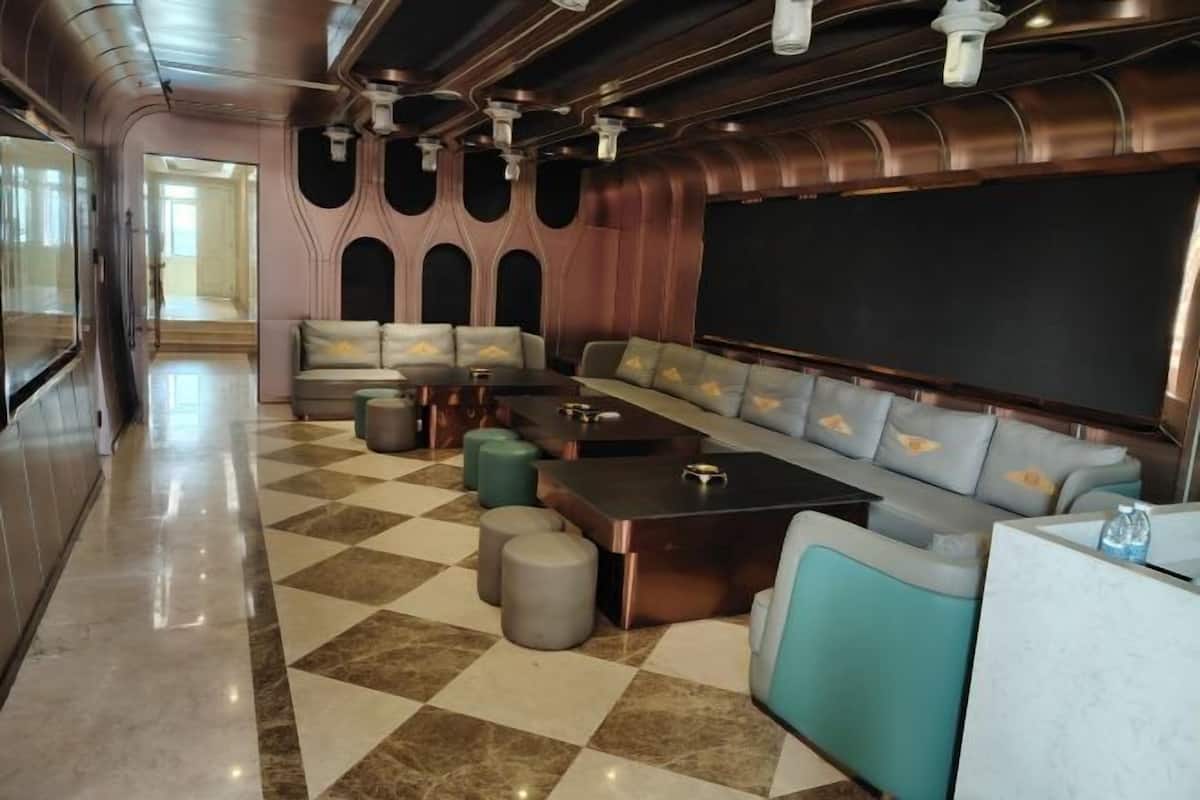 Un salon spacieux et moderne, doté d’un sol à carreaux, d’un long espace détente et d’un grand écran mural.