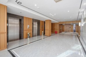Eine moderne Hotelhalle mit Aufzügen, einer Rezeption und einem Marmorboden.