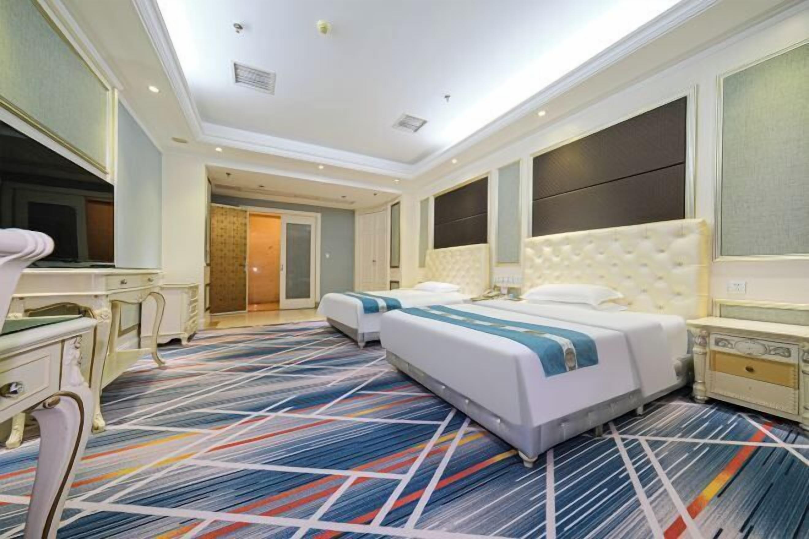 A hotel room with a large bed, a desk, and a television.